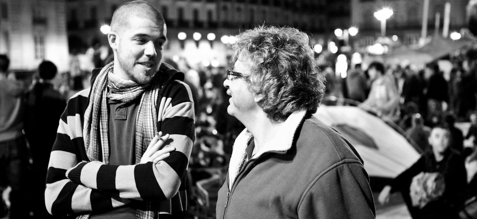 two men talking in a crowd at night