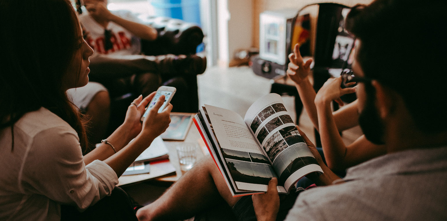 people sitting around a table with smartphone and magazine