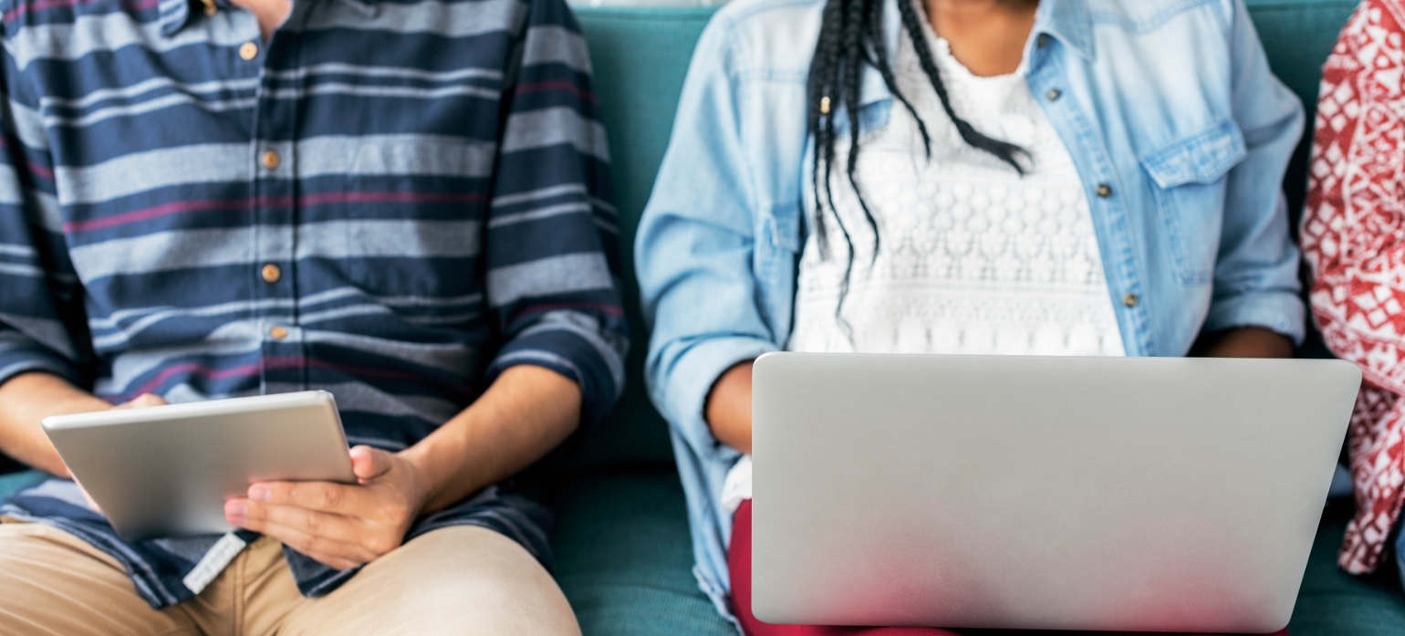 people sitting on couch reading on tablet and laptop