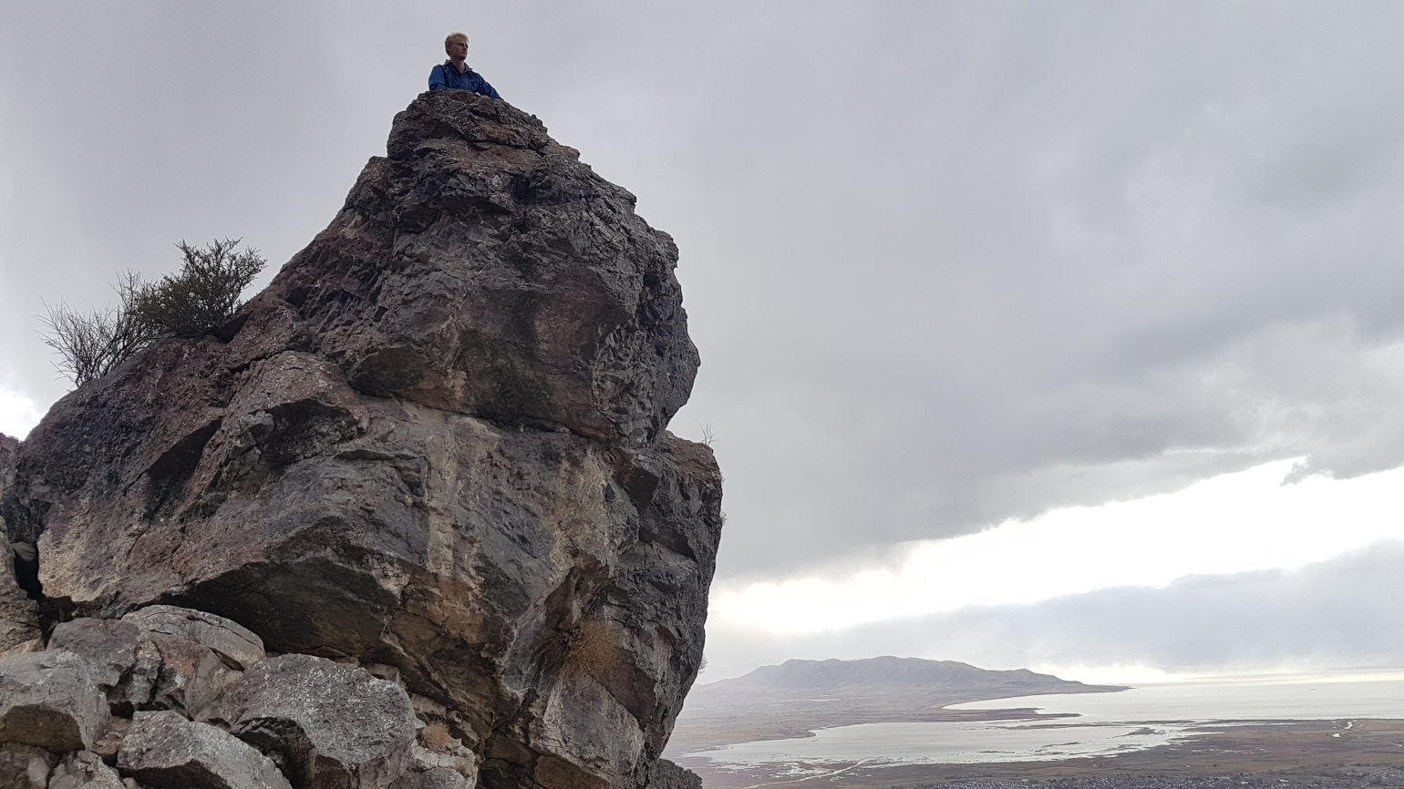 Person on boulder overlooking valley with lake