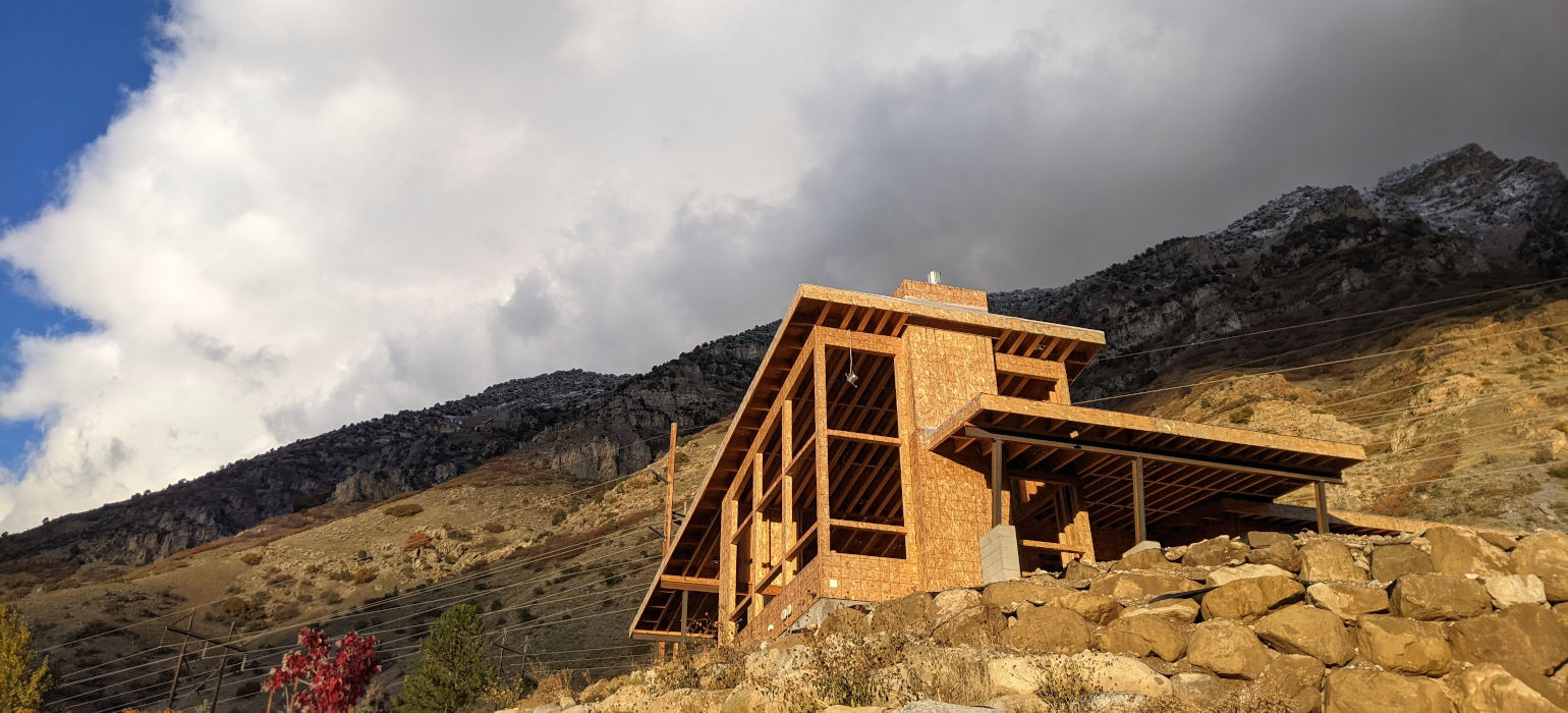 The frame of a house in front of a mountain range