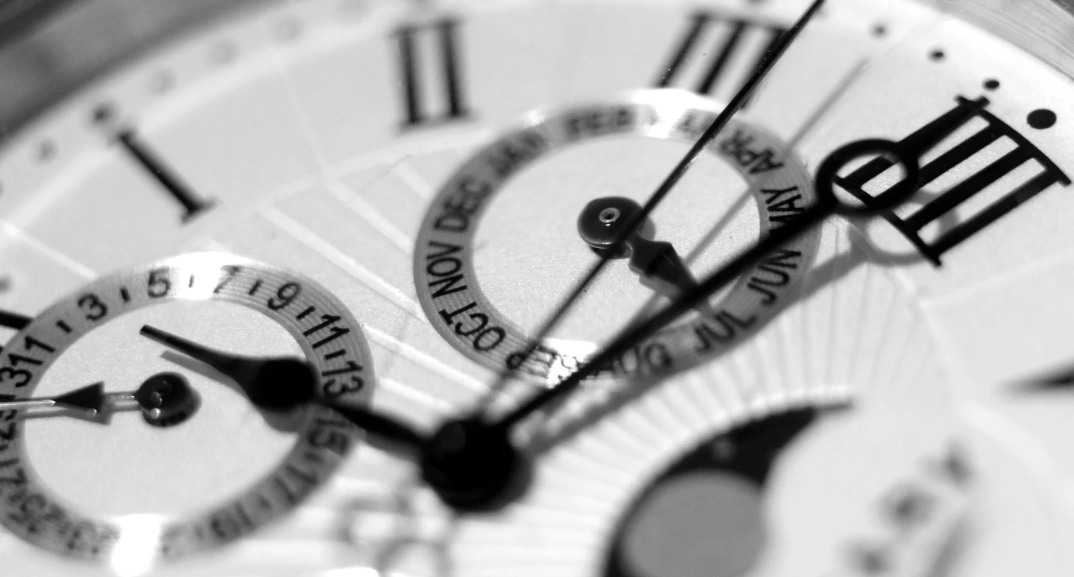 Close-up view of mechanical watch with roman numerals and day of month and month pointers