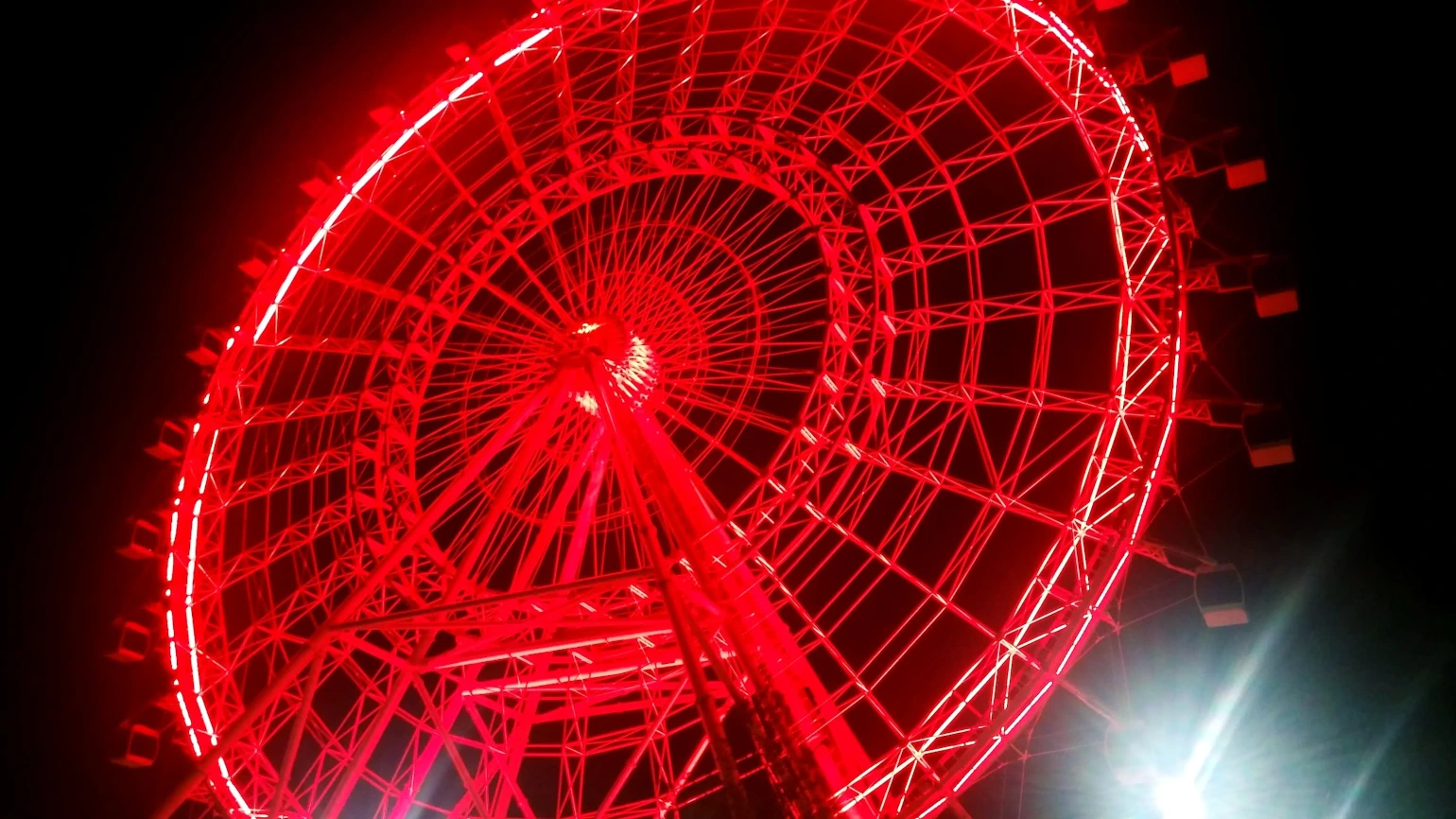 A ferris wheel lit up by red lights at night