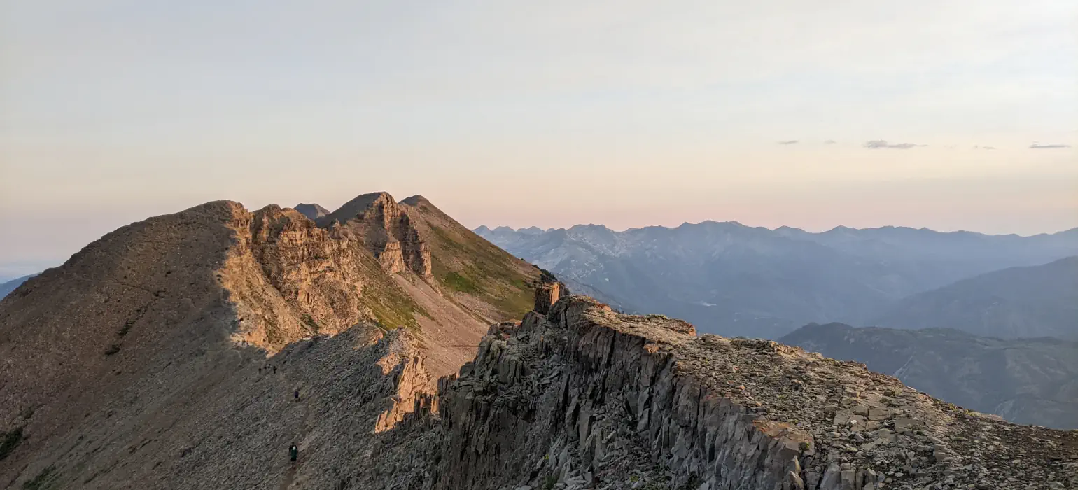 A mountain ridge. One side of the ridge is still covered in shadows, while the sunrise illuminates the other side.