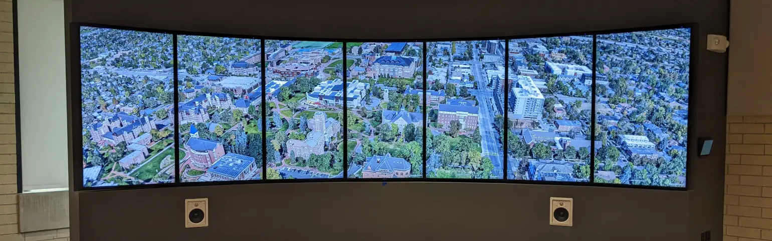 A close-up of the DU visionport. Two speakers are visible in the front of the cabinet. The seven displays show University of Denver’s campus with 3D models in Google Earth.