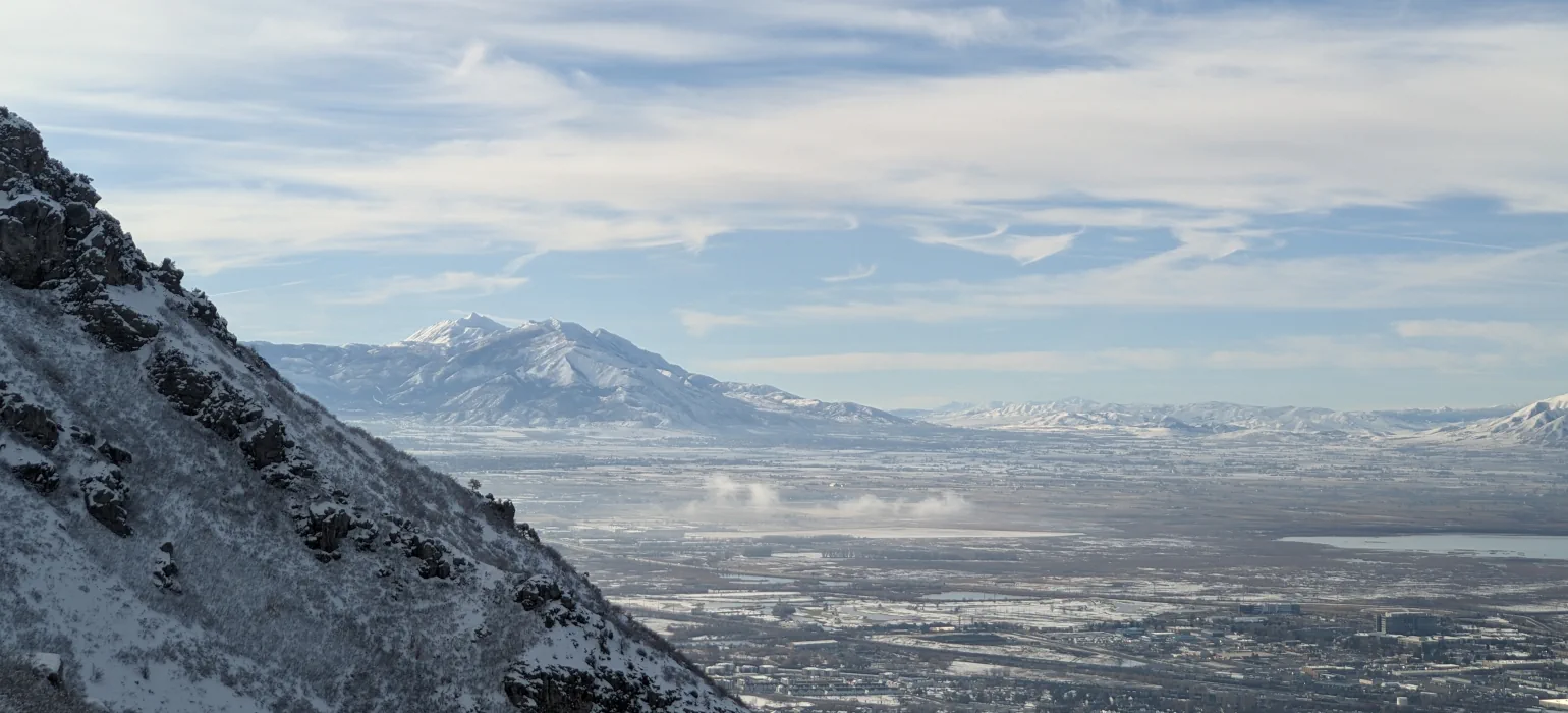 A pale winter morning, looking out over a valley from a mountainside