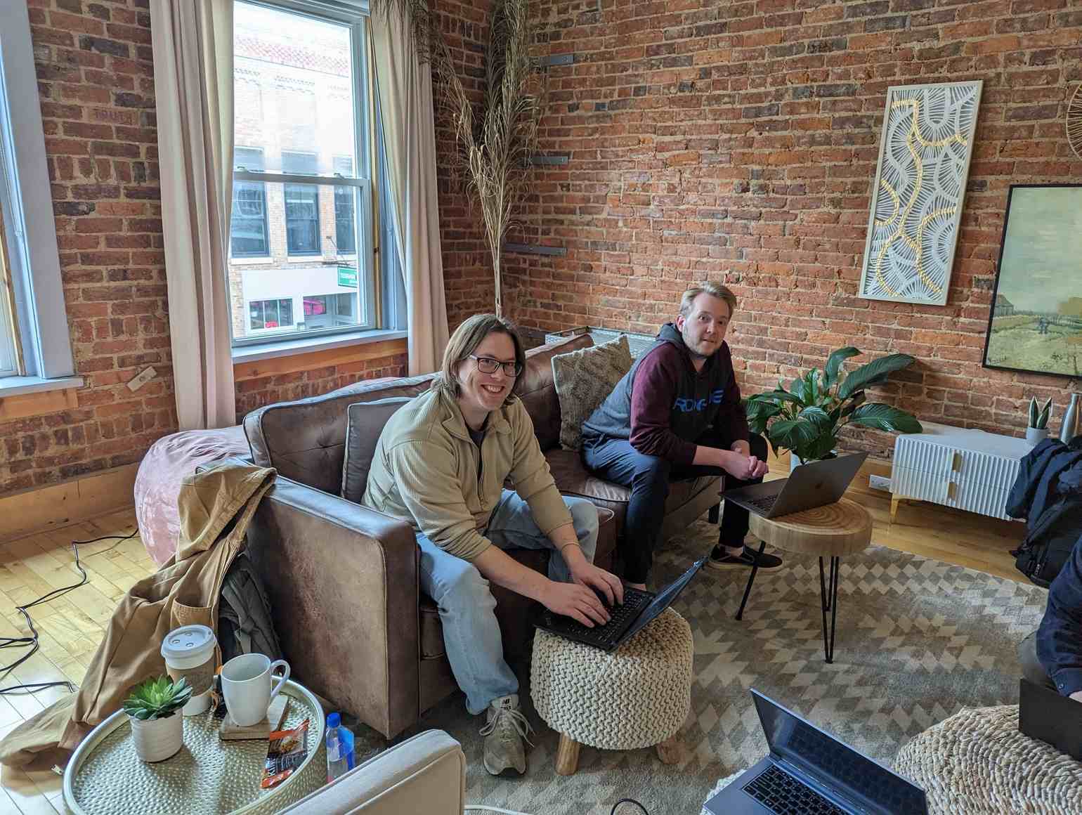 Casablanca, lounge area. Two End Pointers on a leather couch look up from their laptops and smile at the camera.