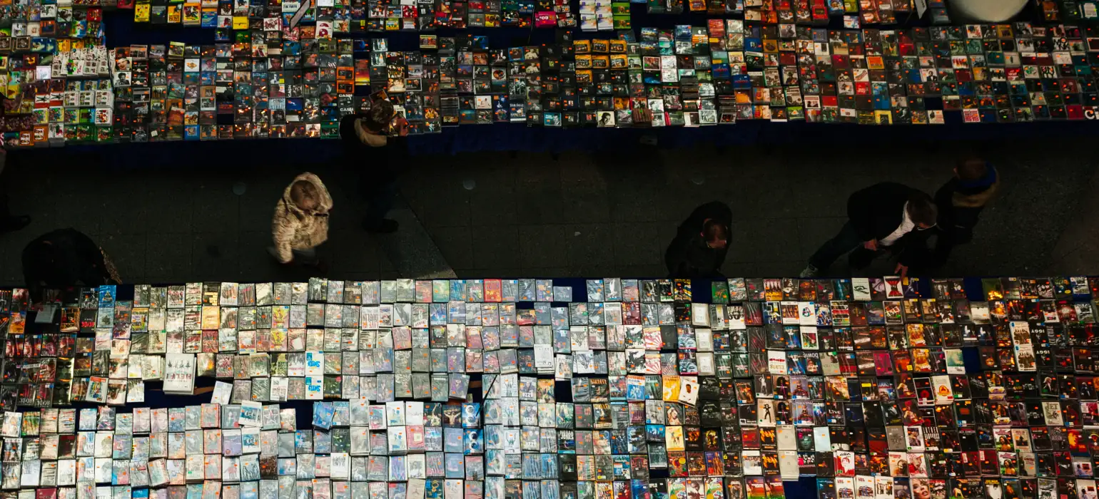 An overhead shot of a market full of thousands of colorful DVD cases. Several people peruse the wares in an aisle