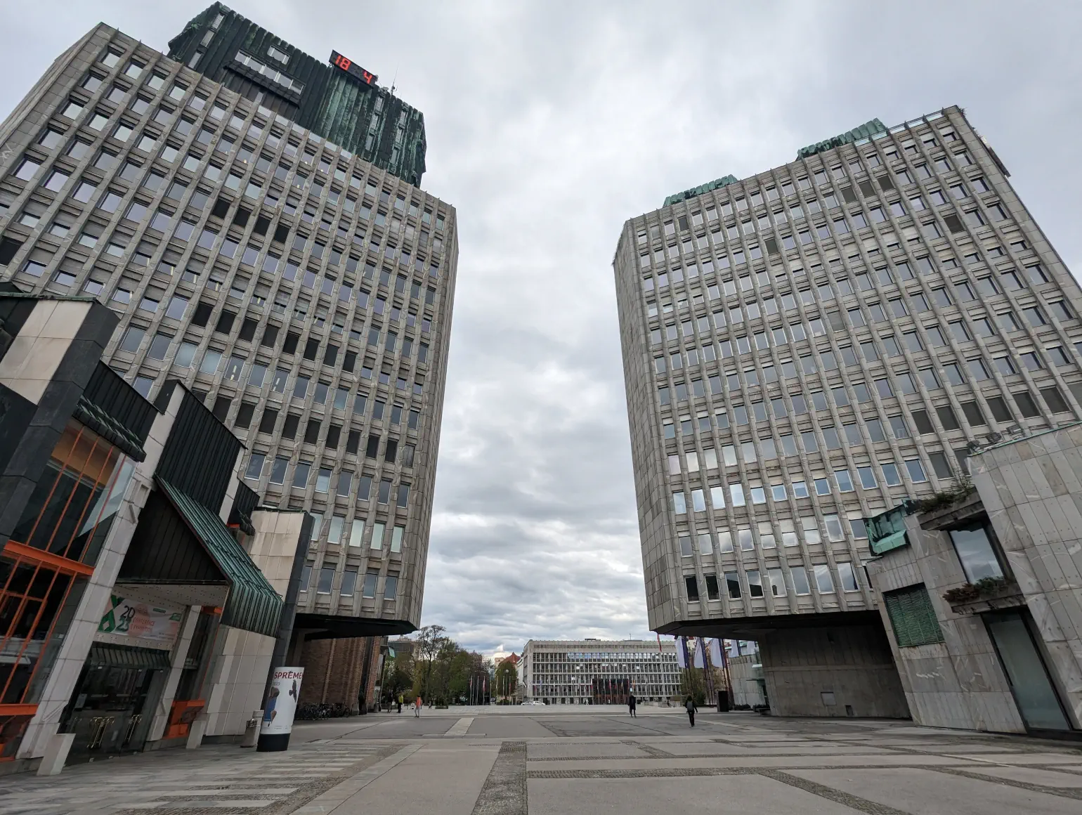 Two brutalist concrete high-rise buildings tower over a concrete square