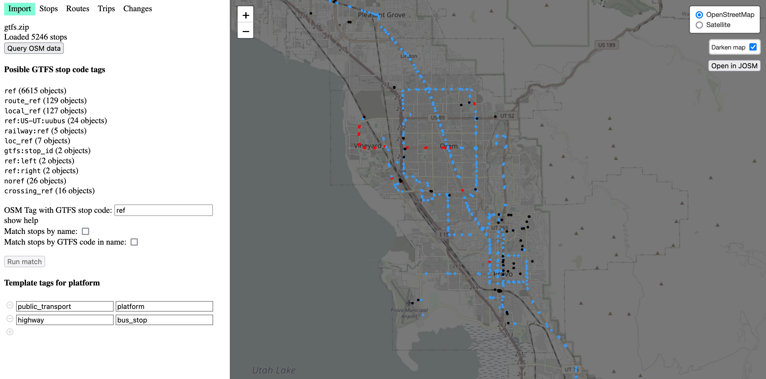 The OpenStreetMap GTFS editor. The right side is a map with a darkened map, and blue, red, and black dots overlayed along the roads where public transit stops are. In the corner, the map reads “Leaflet | copyright OpenStreetMap”. It has controls to zoom, change between satellite and OpenStreetMap, darken the map, and open in JOSM. The left side has navigation buttons reading “Import” (which is selected), “Stops”, “Routes”, “Trips”, and “Changes”. Below there is text on several lines: “gtfs.zip. Loaded 5246 stops” then a button reading “Query OSM data”. Then, “OSM Tag with GTFS stop code: 