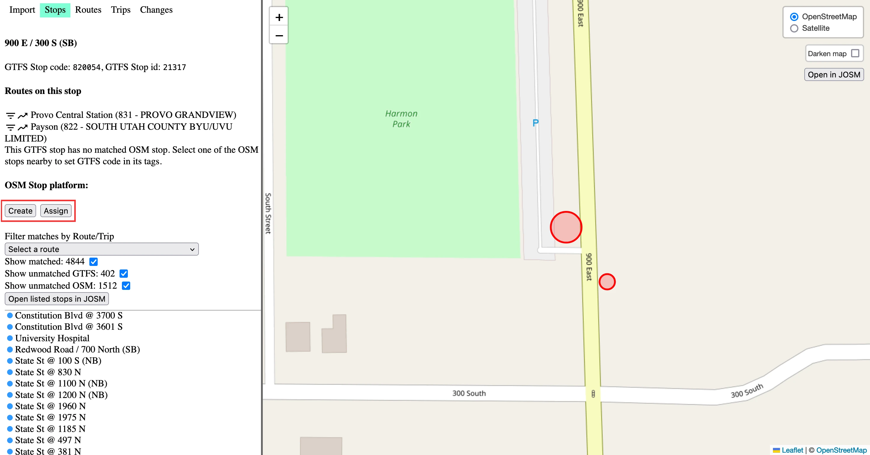 The OSM editing app. The “Stops” tab is selected. In the map, there are red circles on either side of a road. One is larger than the other, indicating its selection. Text in the bar on the left reads: “900 E / 300 S (SB)”, then “GTFS Stop code: 820054, GTFS Stop id: 21317”. Then, “Routes on this stop: Provo Central Station (831 - PROVO GRANDVIEW)” with a filter icon and a rising arrow icon. There is another similar stop. Then “This GTFS stop has no matched OSM stop. Select one of the OSM stops nearby to set GTFS code in its tags”. Then, “OSM Stop platform:” and two buttons reading “Create” and “Assign”. These buttons are highlighted. Then there are stop filter options.